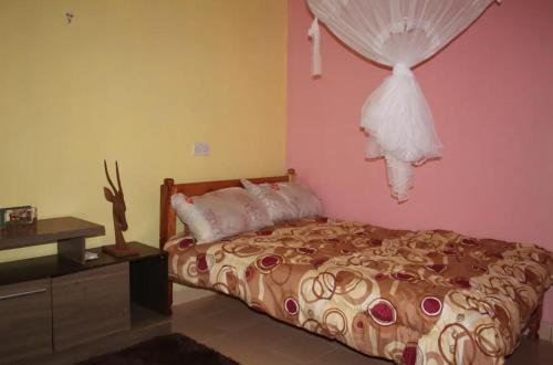 ein Schlafzimmer mit einem Bett mit einem an der Wand hängenden Kleid in der Unterkunft Ojac Guest House - Iten in Iten
