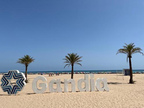 a sign on a sandy beach with palm trees at EUROSOL Vacaciones PLAYA GANDIA in Playa de Gandia