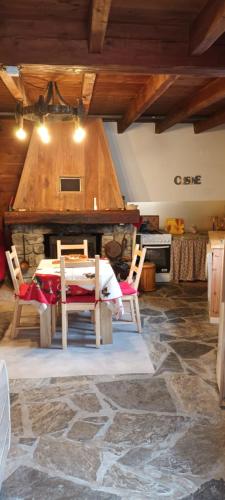 une salle à manger avec une table et une cheminée en pierre dans l'établissement Maison de montagne 2 à 8 couchages proche Barcelonette, à Condamine-Châtelard