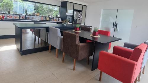 ein Esszimmer mit einem schwarzen Tisch und roten Stühlen in der Unterkunft Fazenda de Jehne - Casa completa in Camamu