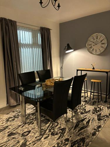 a dining room with a table and chairs and a clock at Manor House in Belfast