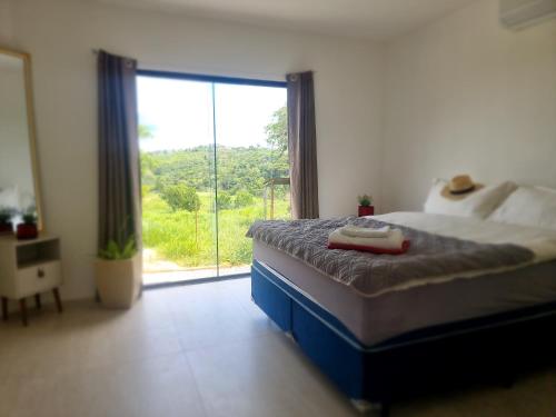 ein Schlafzimmer mit einem Bett und einem großen Fenster in der Unterkunft Fazenda de Jehne - Casa completa in Camamu