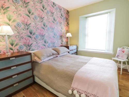 a bedroom with a bed with a floral wallpaper at Lower Neuk in Dunfermline