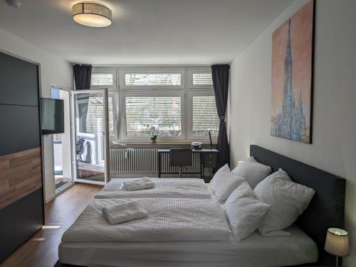 Un dormitorio con una cama con almohadas blancas y una ventana en 100m zum Ulmer Münster: 57m² Wohnung an der Blau, en Ulm