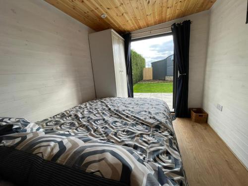 a bed in a room with a large window at Maple Lodge Quirky Salvaged Railway Carriage with Hot Tub in Boston