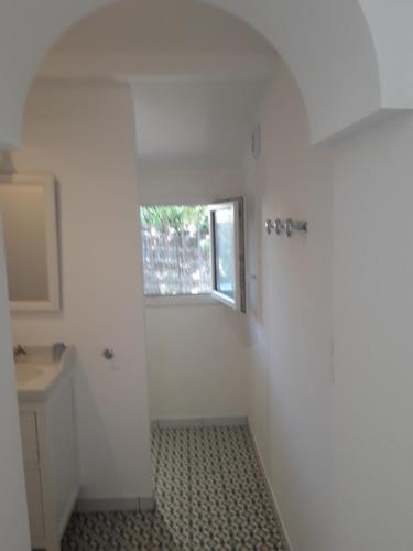 a white bathroom with a sink and a window at villa les Arbousiers in Vieux-Boucau-les-Bains