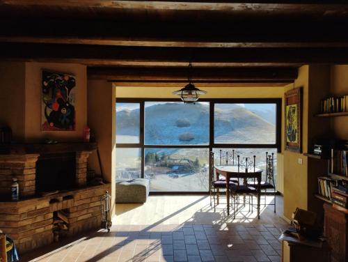 a dining room with a table and a large window at La Kumari in Pintura di Bolognola