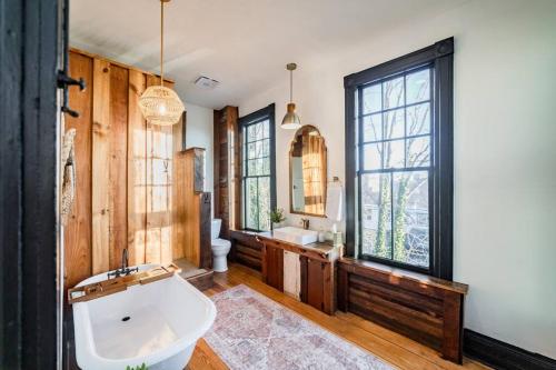 a bathroom with a tub and a sink and a mirror at Grand Historic Downtown Home that Gives Back in Lynchburg