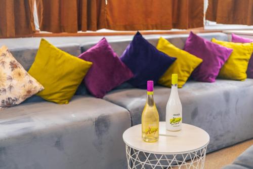 two bottles on a table next to a couch with colorful pillows at Pontonul de pe Dunăre Giurgiu in Giurgiu