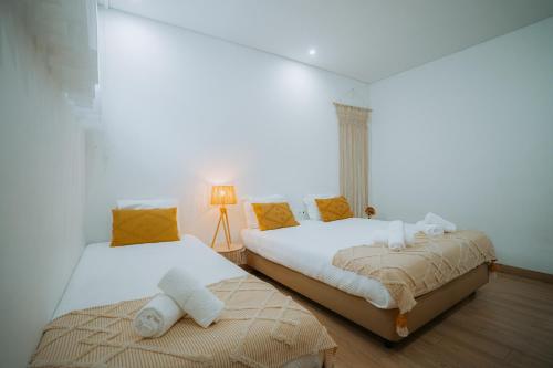 Duas camas num quarto com paredes brancas em Estação do Parque em Santa Maria da Feira