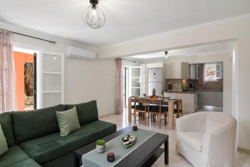 a living room with a green couch and a kitchen at Spiros Holidays House in Doukádes