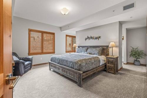 a bedroom with a large bed and a chair at Spring Creek Spacious Luxury King One Bedroom plus Den at White Spruce Lodge in Canmore