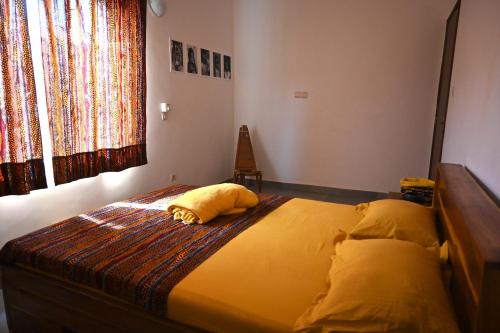 ein Schlafzimmer mit einem Bett mit gelbem Kissen darauf in der Unterkunft Les Amazones Rouges Chambre Jaune in Ouidah