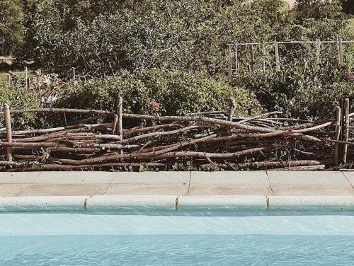 a fence made of logs next to a swimming pool at Maison Magda in Ambierle