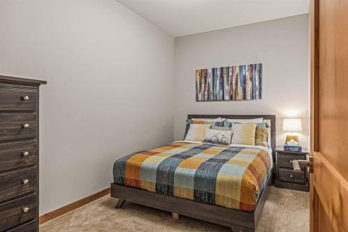 a bedroom with a bed and a painting on the wall at Spring Creek Spacious Luxury King One Bedroom plus Den at White Spruce Lodge in Canmore
