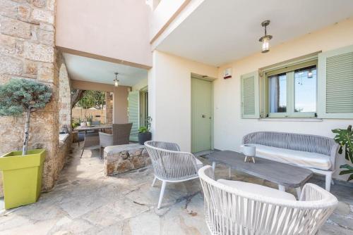 a patio with white chairs and a table and a building at Διαμέρισμα με πισίνα στην Αρτέμιδα in Vravrona