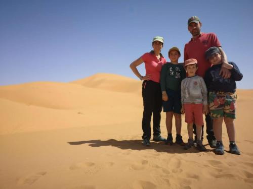 rodzina stojąca w piasku na pustyni w obiekcie Camels House w mieście Merzouga