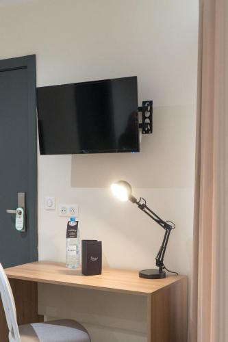 a desk with a lamp and a tv on a wall at Hôtel AL AFIFA in Dakar