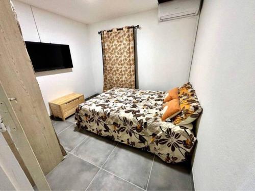 1 dormitorio pequeño con 1 cama y TV en Le p’tit Jack, en Saint-Joseph