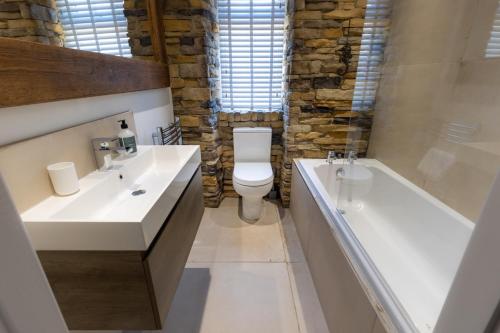 a bathroom with two sinks and a toilet and a tub at Dene Croft Cottage in Hexham