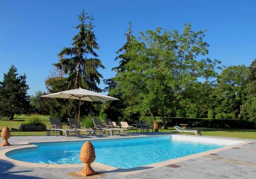 - une piscine avec un parasol, des chaises et une table dans l'établissement Maison hébergement pour 15 personnes, à Montaut-de-Crieux