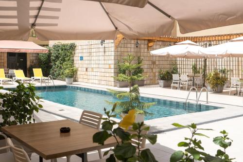 a swimming pool with a table and chairs and umbrellas at Hôtel AL AFIFA in Dakar