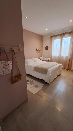 een slaapkamer met een wit bed en een raam bij La maison sous les pins in Saint-Laurent-dʼAigouze