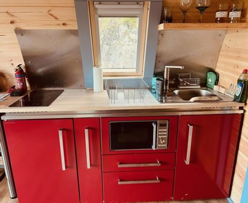 cocina con armarios rojos y microondas en Hidden Hut - Aros View - Tobermory, en Tobermory