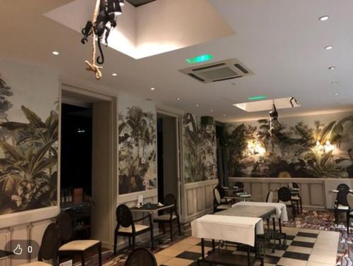 a hair salon with tables and chairs and paintings on the walls at Forgeron de seclin in Seclin