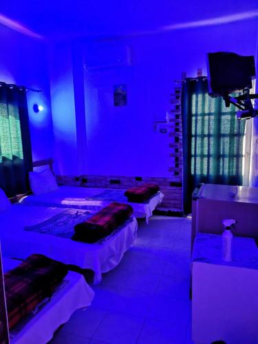 a blue room with two beds and a tv at Four Seasons Hotel in Hurghada