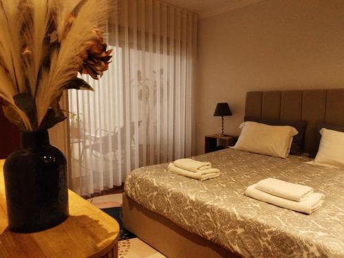 a bedroom with a bed with towels and a vase with flowers at RR Residence in Viana do Castelo