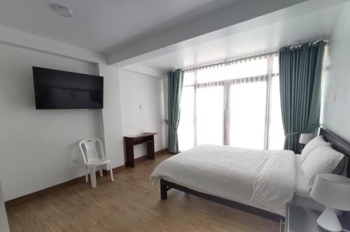 a hotel room with a bed and a television at La Casa de Algodon in Huacho