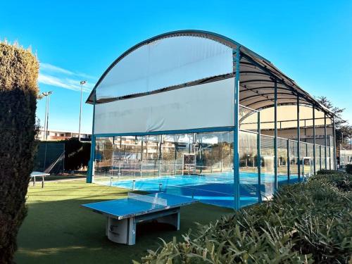 una pista de tenis con una mesa azul frente a un edificio en Agatha, appartement T2 premium tennis center, en Cap d'Agde