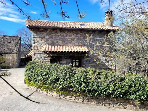 a stone building with a hedge in front of it at El Pajar de la Plaza in Guaso