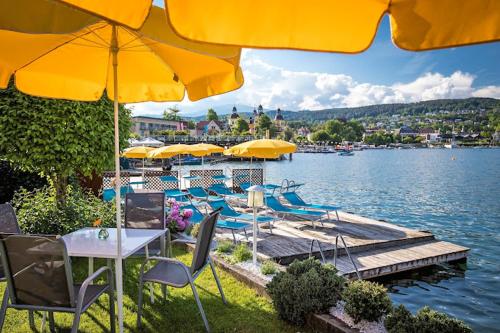 a group of tables and chairs with umbrellas on a dock at Beachhaus Velden in Velden am Wörthersee