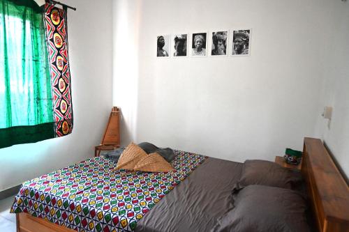 un letto in una camera da letto con immagini appese al muro di Les Amazones Rouges Chambre Verte a Ouidah