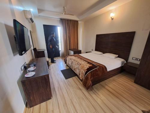 una habitación de hotel con una cama y un hombre de pie en ella en F2B stay en Mathura