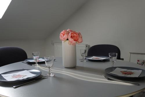 einen Tisch mit Platten und eine Vase mit rosa Blumen in der Unterkunft Ruhige Ferienwohnung in der Kernstadt Laubach in Laubach