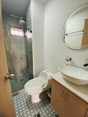 a bathroom with a toilet and a sink and a mirror at Loma Rent Home Guatape in Guatapé