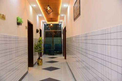 un pasillo con paredes de baldosas blancas y un suelo con una maceta. en Go Guest House Lahore, en Lahore