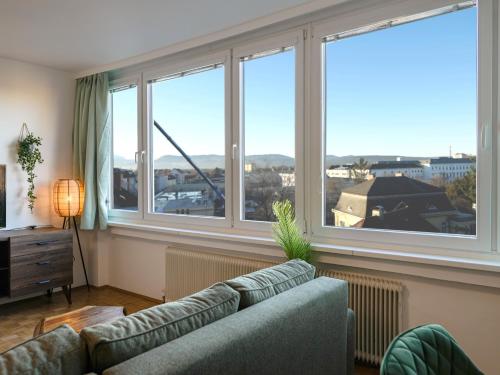 ein Wohnzimmer mit einem Sofa und großen Fenstern in der Unterkunft Spacious Apartments with View & Free Parking in Wiener Neustadt