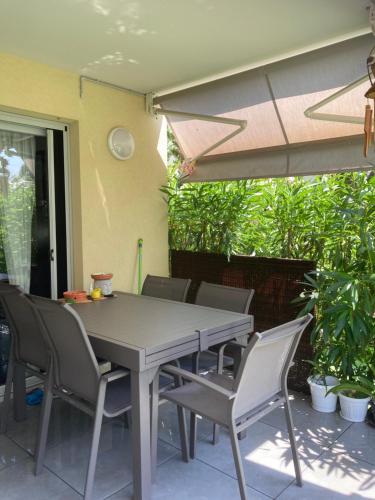 une table avec des chaises et un parasol sur une terrasse dans l'établissement Très belle appartement, à Cagnes-sur-Mer