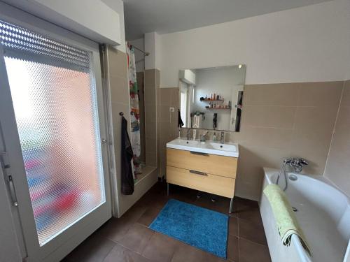 y baño con bañera, lavabo y espejo. en Superbe appartement avec belle terrasse, en Bischheim