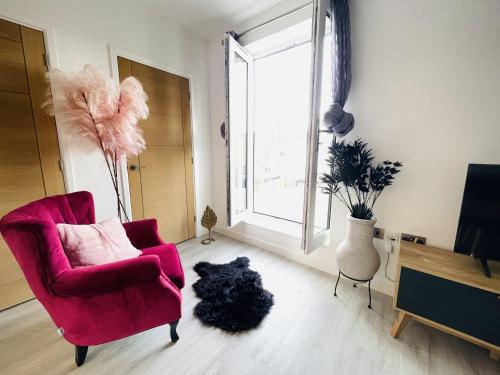 uma sala de estar com uma cadeira rosa e um cão preto em Spacious 4 Bedroom, Wi-Fi, 2 Gardens, Sleeps 8 - Amethyst em Cambridge