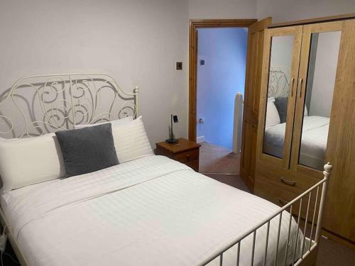 a bedroom with a white bed and a mirror at A secured 3 bedroom family home in Radcliffe