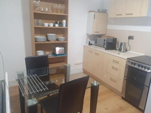 een keuken met een tafel en stoelen en een fornuis bij A secured 3 bedroom family home in Radcliffe