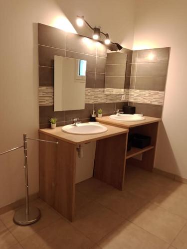 une salle de bain avec deux lavabos et un grand miroir dans l'établissement Villa avec piscine dans un avre de verdure, à Caderousse