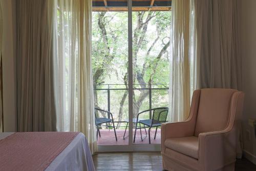 a bedroom with a bed and a chair and a balcony at Hotel Porto do Ribeirão in Iporanga