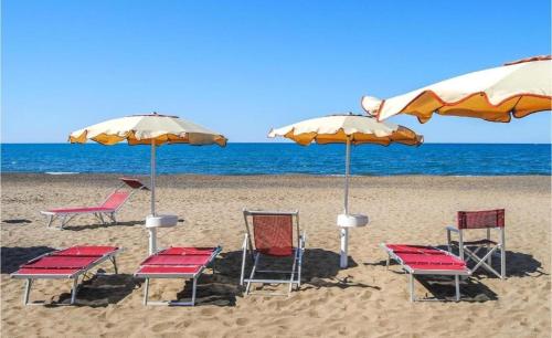 - un groupe de chaises longues et de parasols sur une plage dans l'établissement Luna di mare, à Marina di Bibbona