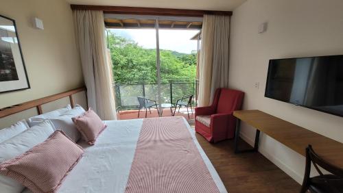 a bedroom with a bed and a television and a balcony at Hotel Porto do Ribeirão in Iporanga
